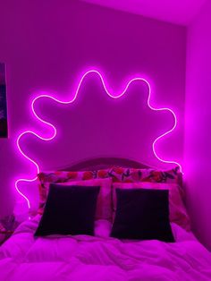 a bed that has some lights on the headboard and pillows in front of it