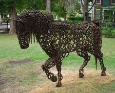 a horse made out of metal is standing in the grass