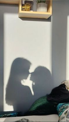 the shadow of a man and woman in front of a white wall with bookshelves