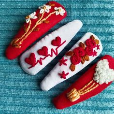 three red and white hair clips with flowers on them sitting on a blue cloth surface