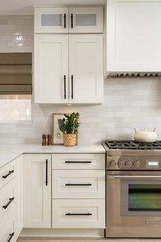 a kitchen with white cabinets and an oven in the center, along with a potted plant on the counter