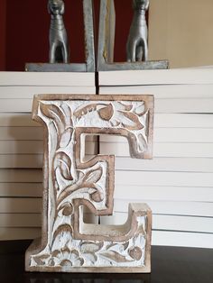 the letter f is carved from wood and sits in front of a mirror on top of a table