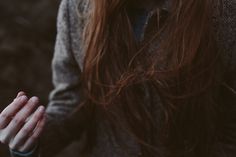 a woman with long red hair holding her hands together