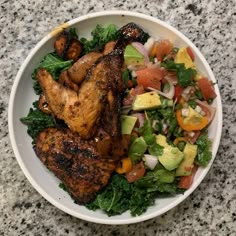 a white bowl filled with meat and veggies on top of a marble counter