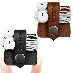 two pieces of leather with earbuds attached to them, one being held in the other hand