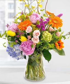 a vase filled with lots of different colored flowers