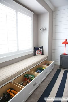 a white bench with drawers underneath it in a room next to a blue and white striped rug