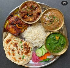 a plate filled with different types of food on top of a metal tray next to cucumbers and sauces