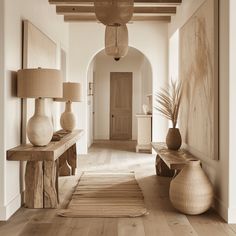 a hallway with two vases on either side of the wall and a rug on the floor