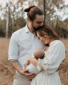 a man and woman holding a baby in their arms