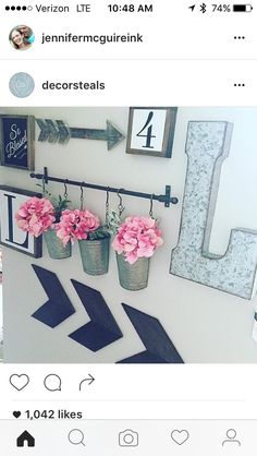 flowers are hanging on the wall in front of a number one sign and two vases with pink flowers