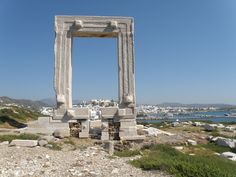 a stone structure sitting on top of a rocky hillside next to the ocean and city