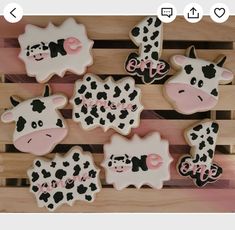 decorated cookies are arranged in the shape of cows and giraffes on a wooden surface