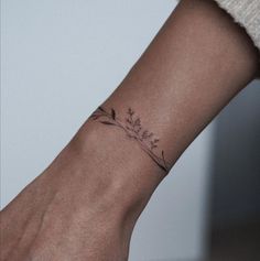 a woman's wrist with a small flower tattoo on the left side of her arm