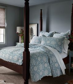 a bed with blue and white bedspread in a bedroom next to a window