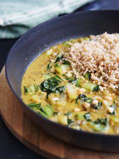 a bowl filled with rice and vegetables on top of a wooden cutting board