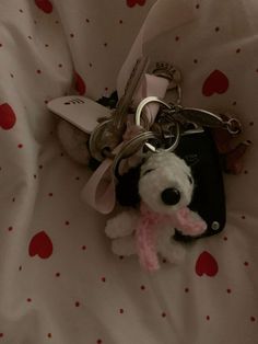 a stuffed animal keychain with a pink scarf around it's neck on a bed