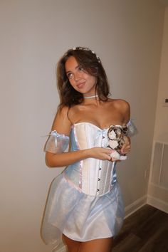 a woman in a corset holding a teddy bear and posing for the camera