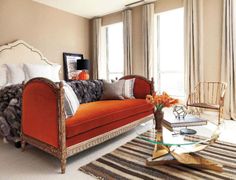 a living room with orange couches and striped rugs on the floor in front of large windows