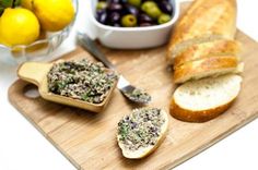 sliced bread and olives on a cutting board next to a bowl of olives