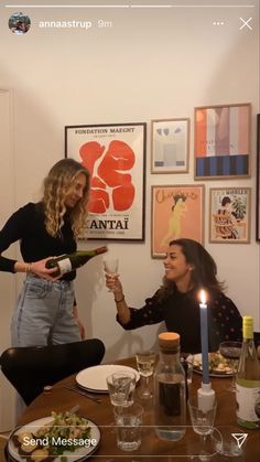 two women sitting at a table holding wine glasses