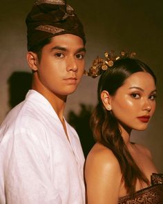 a young man and woman standing next to each other wearing head coverings on their heads