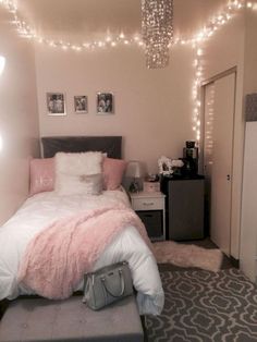 a bedroom decorated in pink and grey with lights strung above the bed, luggage on the floor