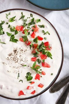 a bowl filled with yogurt and garnished with fresh herbs