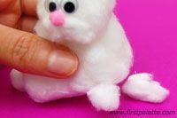 a tiny white cat sitting on top of a pink surface