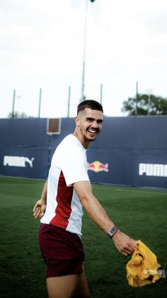 a man in red and white shirt holding onto a yellow glove on a soccer field