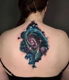 the back of a woman's shoulder with an abstract galaxy and stars tattoo on it