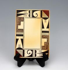 a wooden plaque with an abstract design on it's sides and a gold plate in the middle