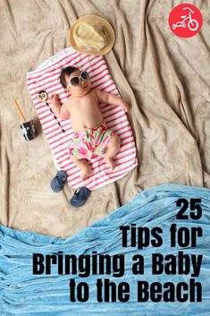 a baby laying on top of a blue blanket next to a hat and sun glasses