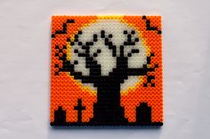 an orange and black beaded square with a tree in the middle on white background