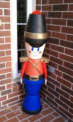 a toy soldier sitting on top of a blue barrel in front of a brick building