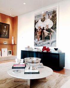 a living room filled with furniture and a painting on the wall above it's coffee table