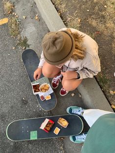 a young boy sitting on top of a skateboard next to a box of food