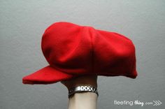 a person's hand wearing a red hat