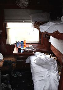 two bunk beds in a small room with white sheets and pillows on the bedding