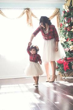 a mother and daughter standing in front of a christmas tree