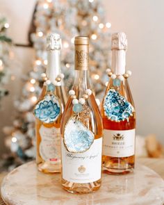 three bottles of wine sitting on top of a table next to a small christmas tree