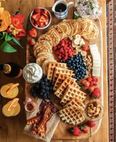 a wooden table topped with waffles, fruit and other foods on top of it