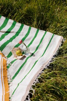 a green and white towel sitting on top of a grass covered field next to a bottle