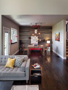 a living room filled with furniture next to a wooden wall