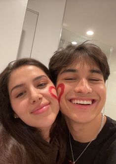 a young man and woman are smiling for the camera with their faces painted to look like hearts