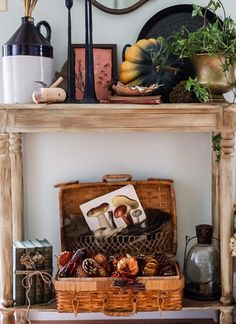 a wooden table topped with a basket filled with lots of autumn items next to a mirror