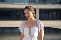 a woman standing in front of a building wearing a white dress