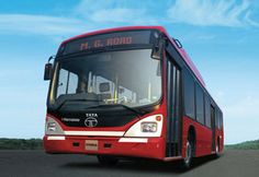 a red bus driving down a road next to a lush green field and blue sky