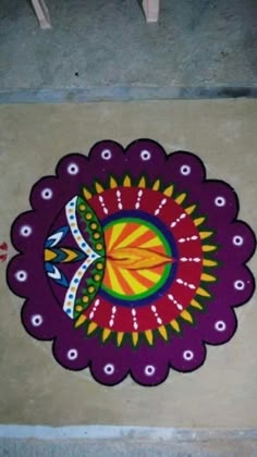 a colorful design on the ground in front of a door with an orange and yellow flower