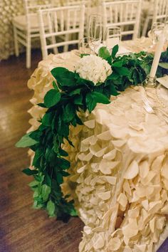 the table is set with white flowers and greenery